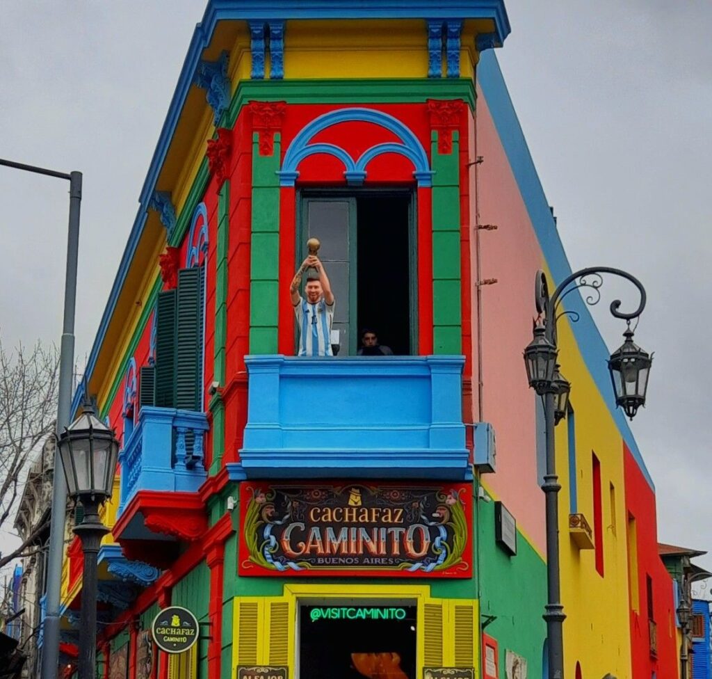 Colorful building in Caminito street museum, La Boca, featuring a statue of Lionel Messi on the balcony